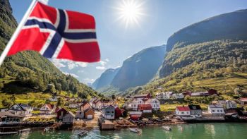 Grafika przedstawiająca norweską flagę z tłem miasteczka poółożonego nad jeziorem w górach